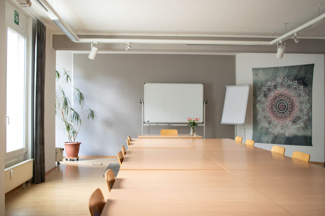 Seminarraum 1: großer Tisch mit Stuhlreihe, Whiteboard und Flipchart